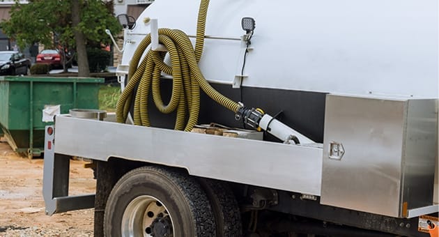 The back end of a work truck with a septic hose attached.