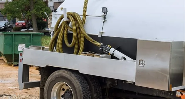 The back end of a work truck with a septic hose attached.