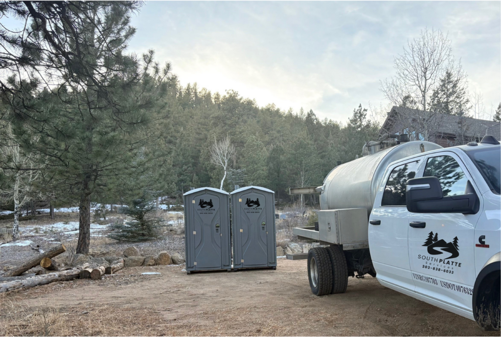 A pair of South Platte Services, LLC portable toilets (porta-potties) sit at a trailhead next to a cleanup truck.